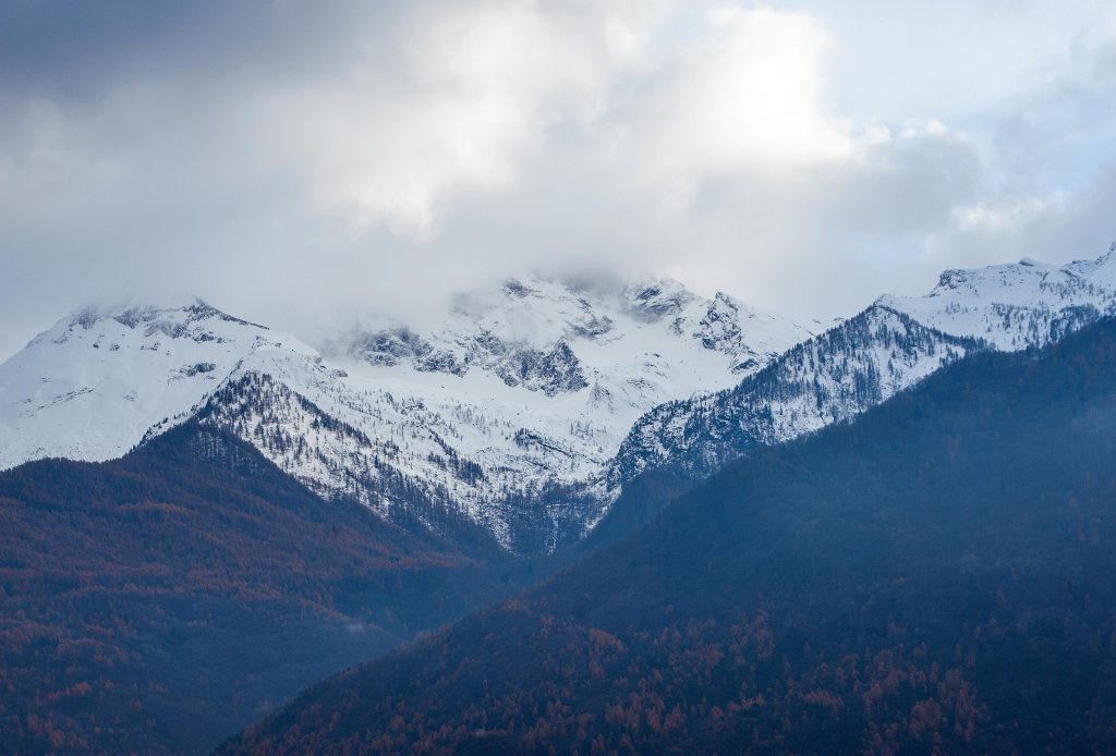 cima di una montagna innevata sotto ad un cielo nuvoloso vista in lontananza