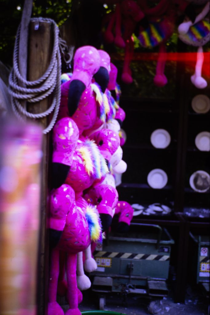 Some flamingos shaped stuffed animals hanging from a wall