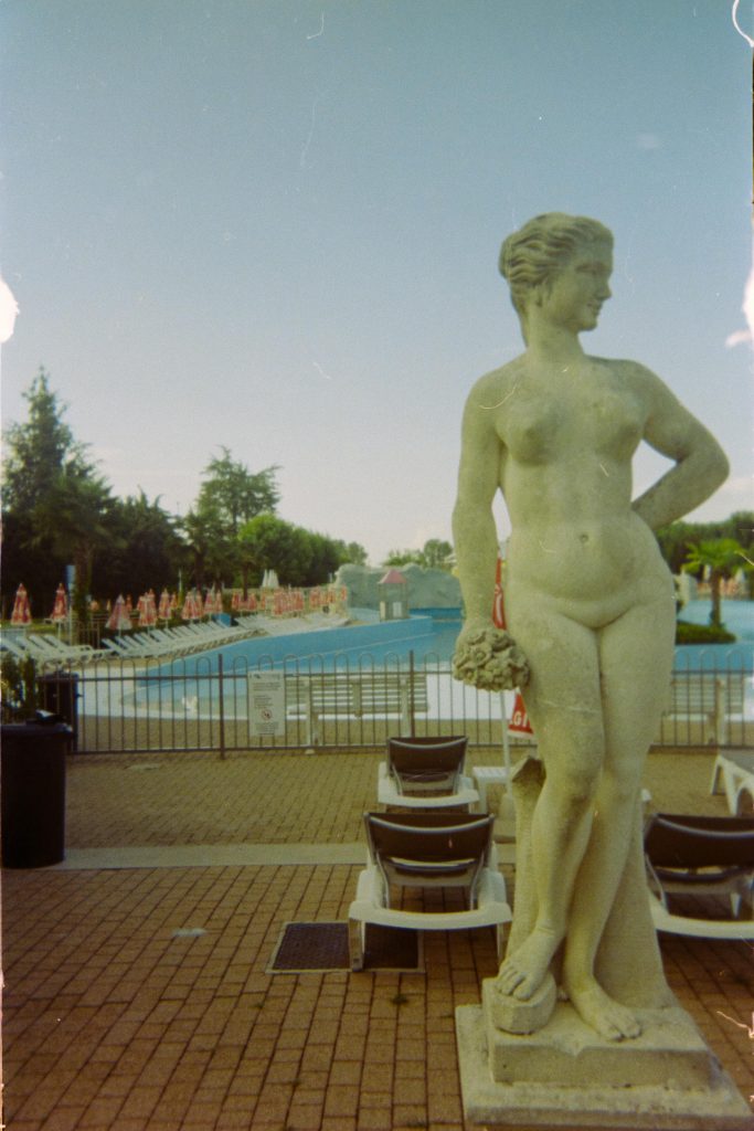 a fake granite statue representing a naked woman in front of a desert pool