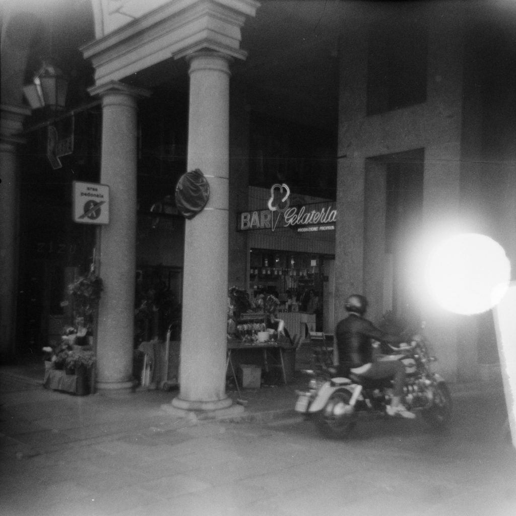 a Cruiser Motorcycle passing under some marble pillars