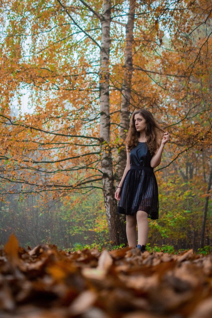 A girl in a black dress in the woods during fall