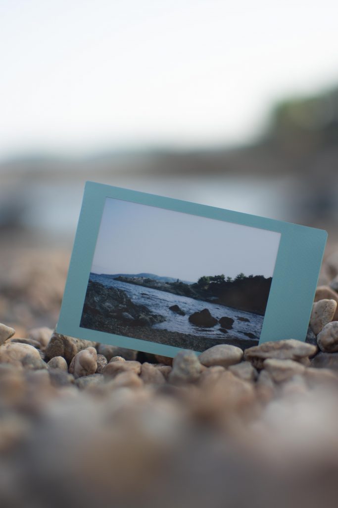 An instant photo representing the landscape of a beach with teal borders lying in the sand 