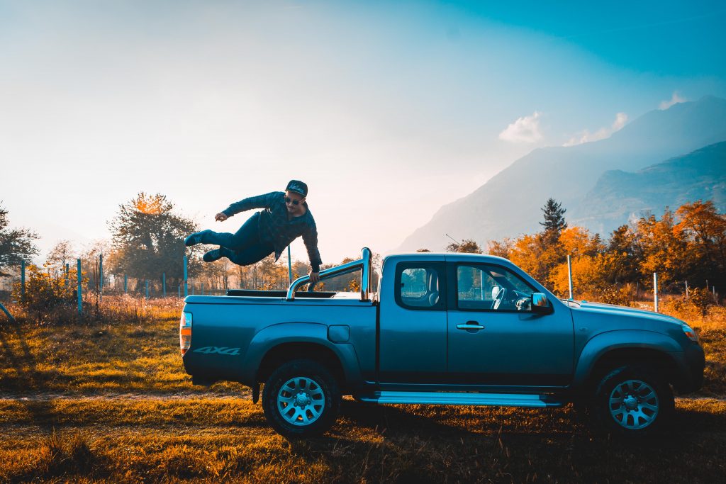 A guy jumping off a pickup truck's bed